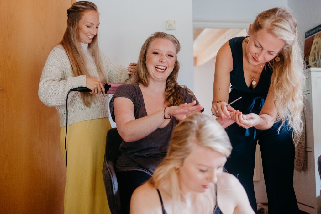 Braut Bea wird am Morgen von ihrer Schwester und den Brautjungfern für die Hochzeit gestylt.