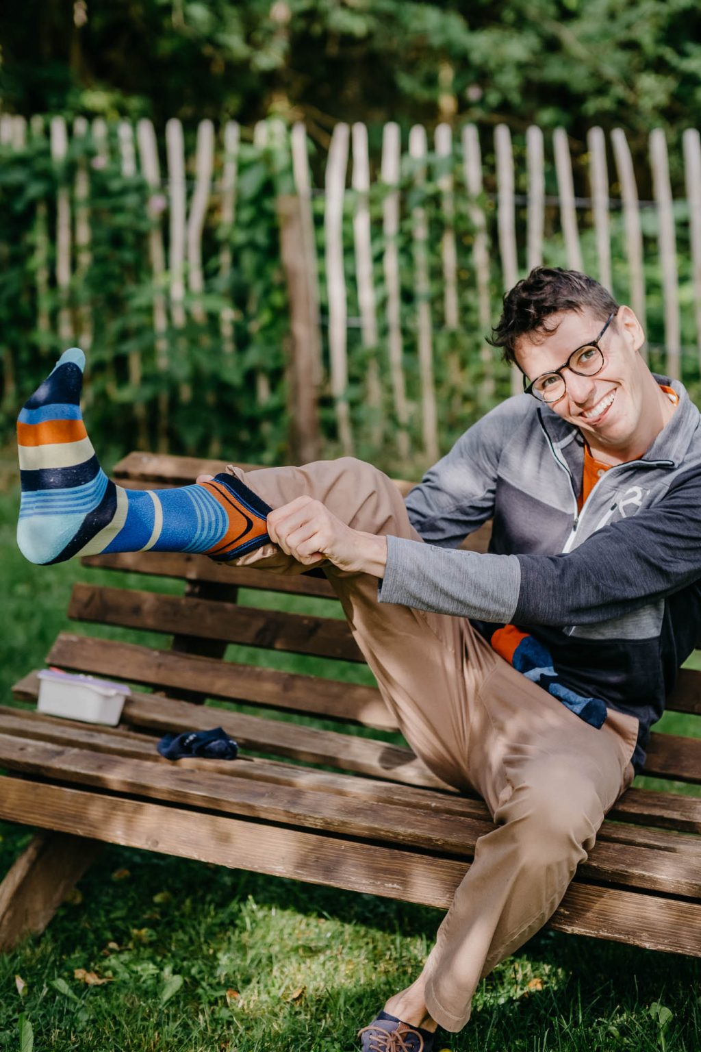 Bräutigam zieht bunte Socken an und lacht verschmitzt in die Kamera