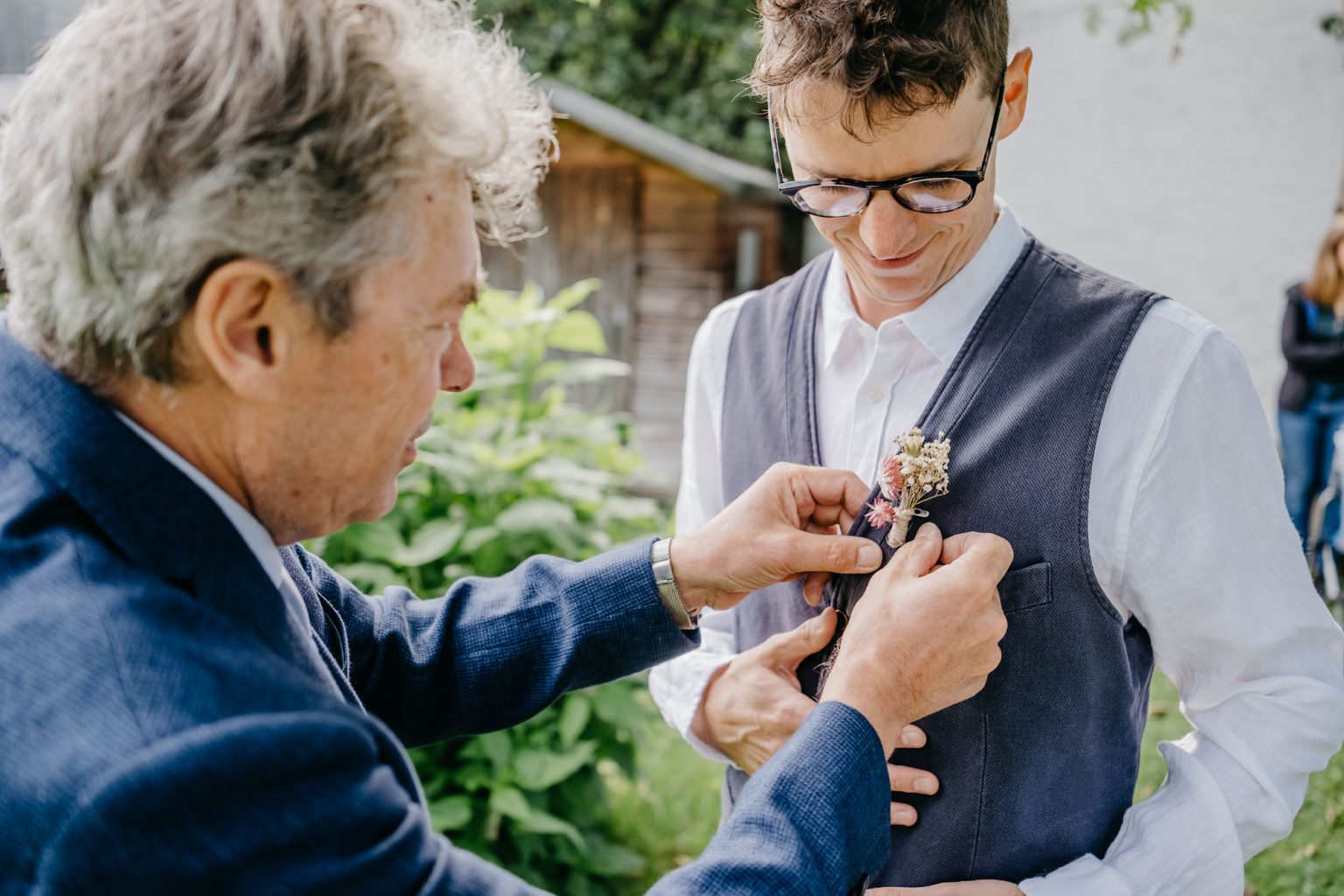 Vater des Bräutigams steckt Ansteckblume an dessen Weste