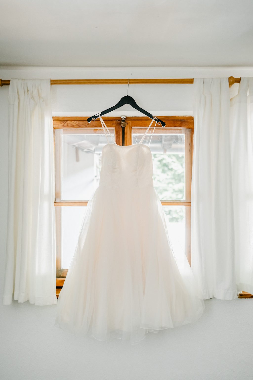 Brautkleid hängt am Fenster aus Holz im Hotelzimmer Alatsee