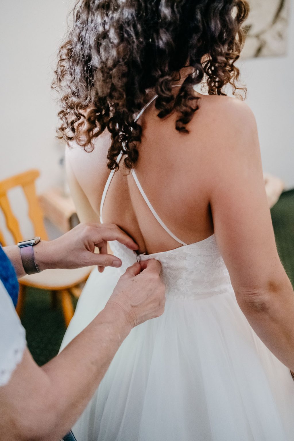 Brautmutter hilft der Braut ins Kleid, Close-up der Hände