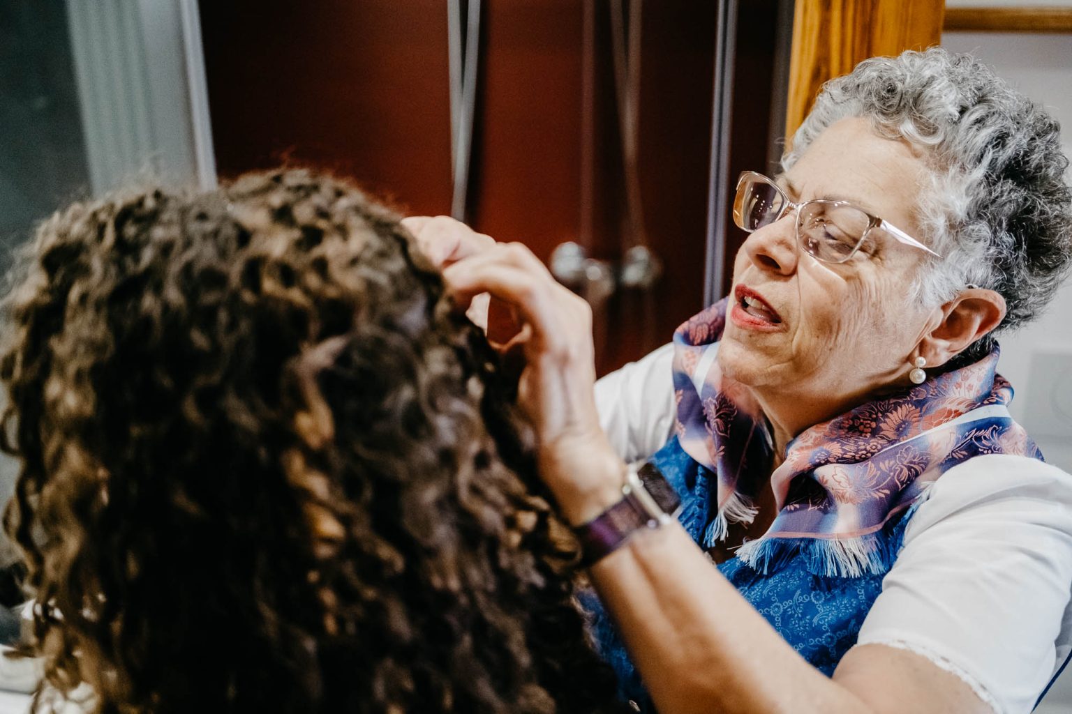 Brautmutter steckt Haarschmuck in die Haare der Braut