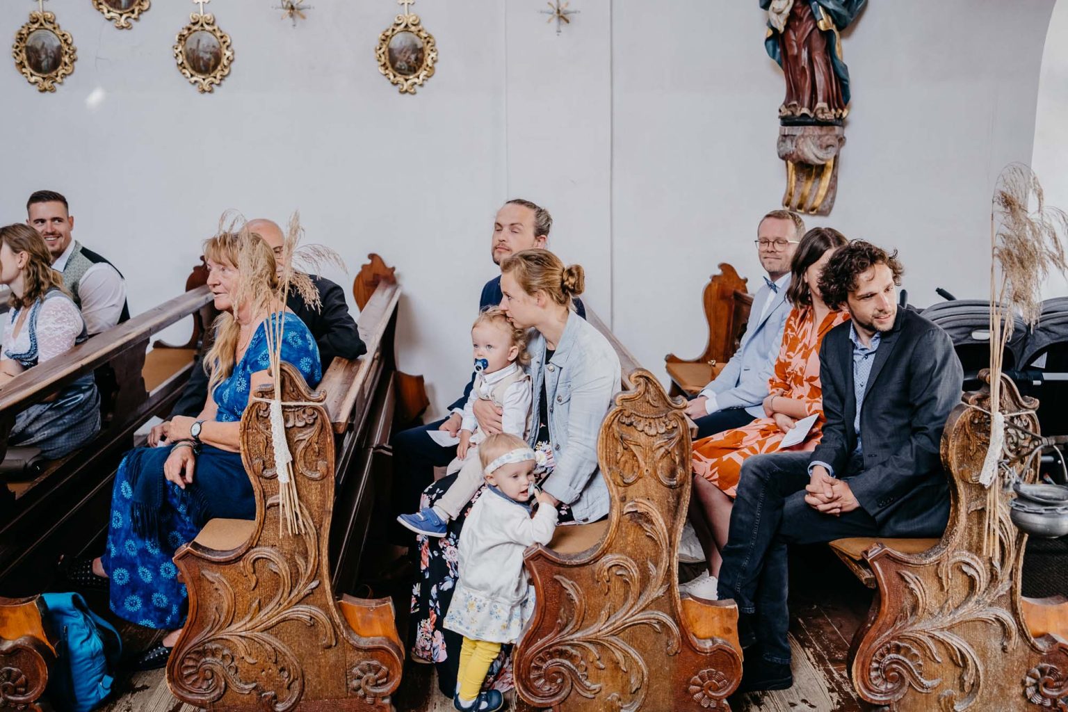 Gäste sitzen in den Kirchenbänken der Spitalkirche und warten