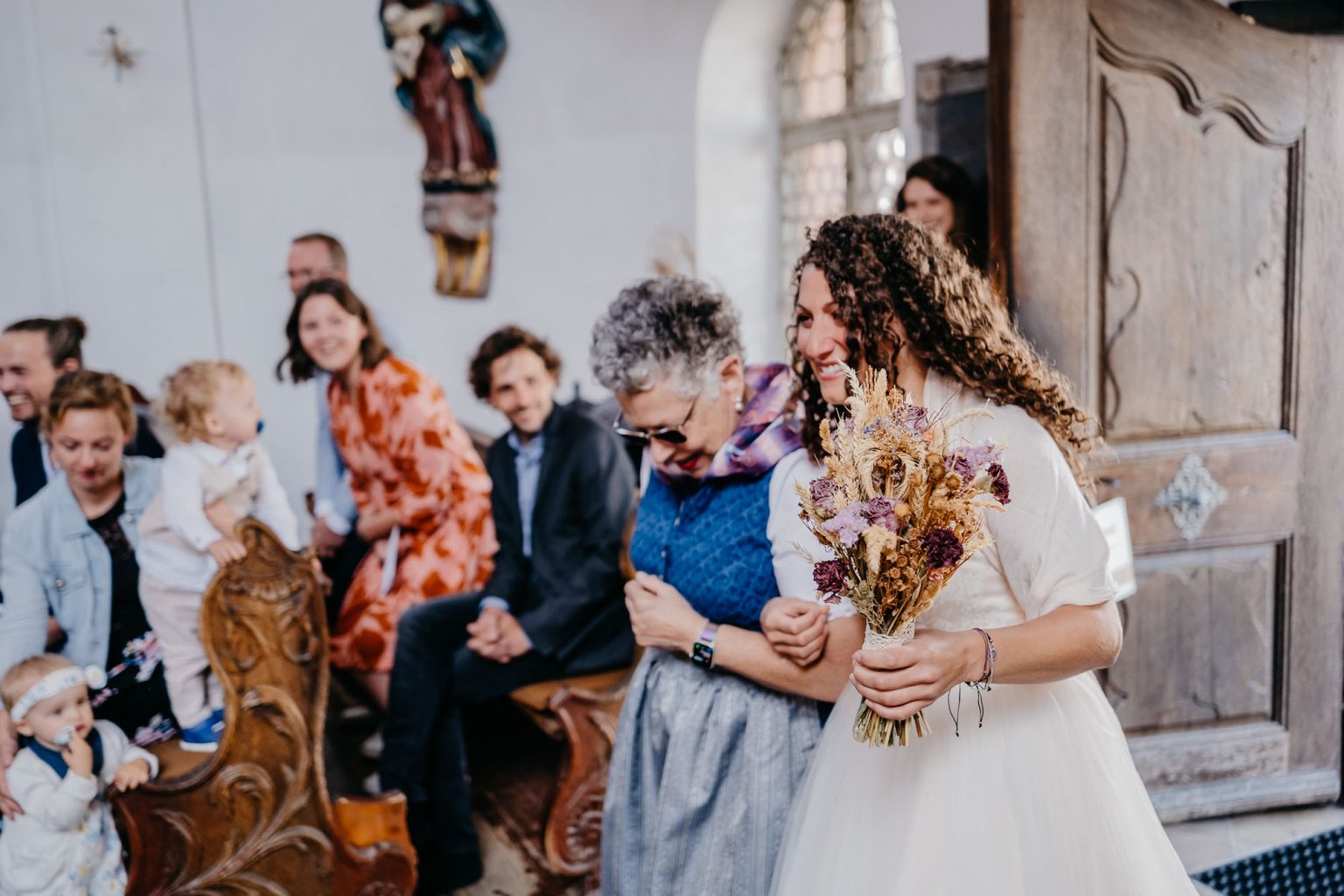 Braut und Brautmutter schreiten im Profil durch die Kirche