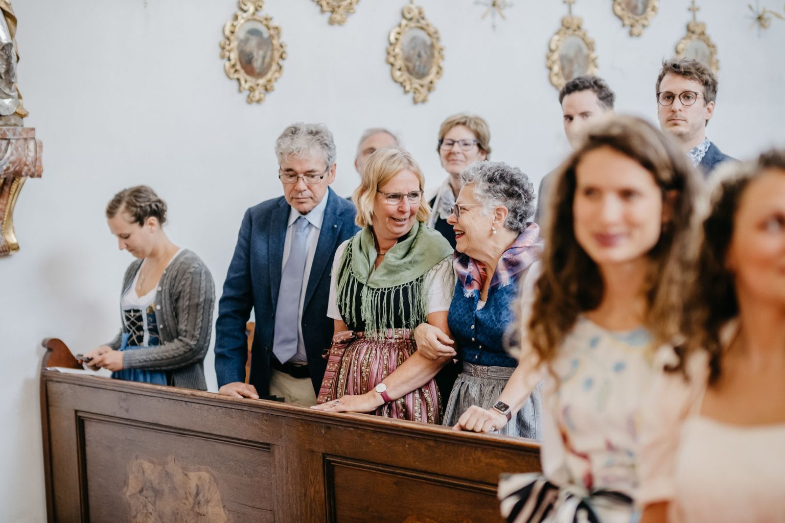 Braut- und Bräutigammutter lachen sich in der Kirchenbank an
