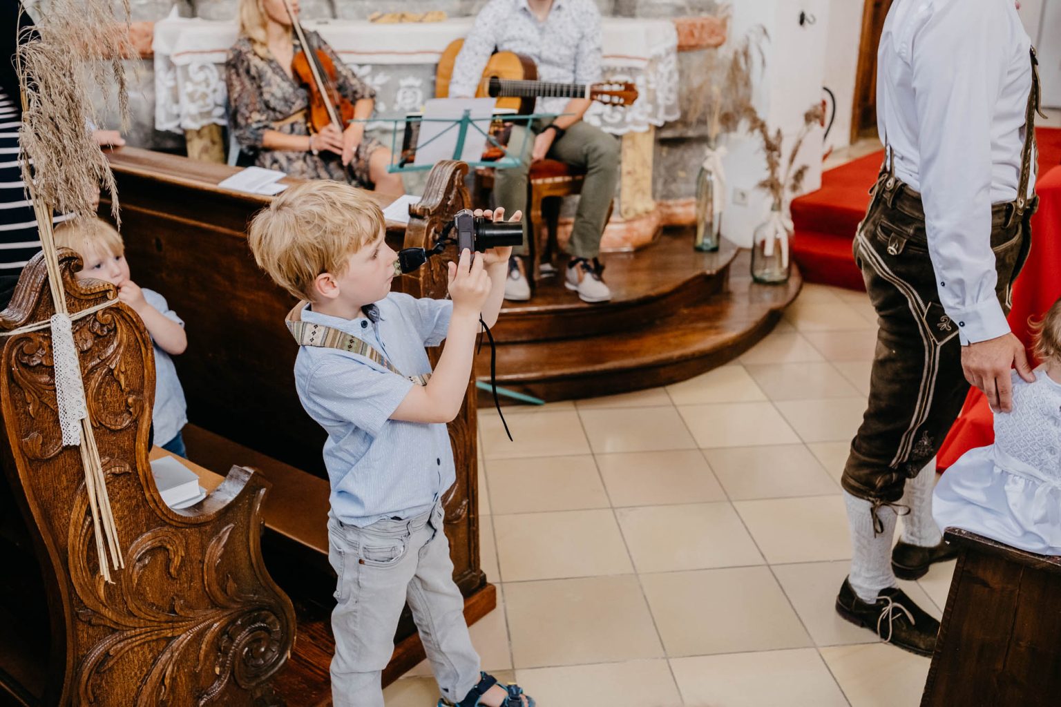 Junge mit Kamera fotografiert das Ja-Wort aus den Kirchenbänken