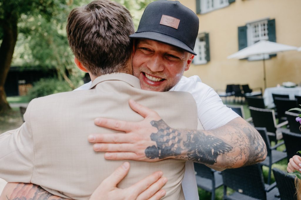 Der Bruder der Braut umarmt emotional den Bräutigam nach der Trauung.
