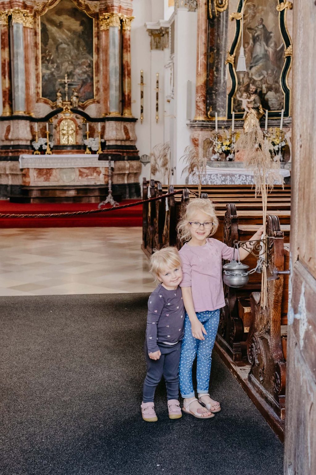 Zwei Mädchen lächeln in der Kirche in die Kamera.