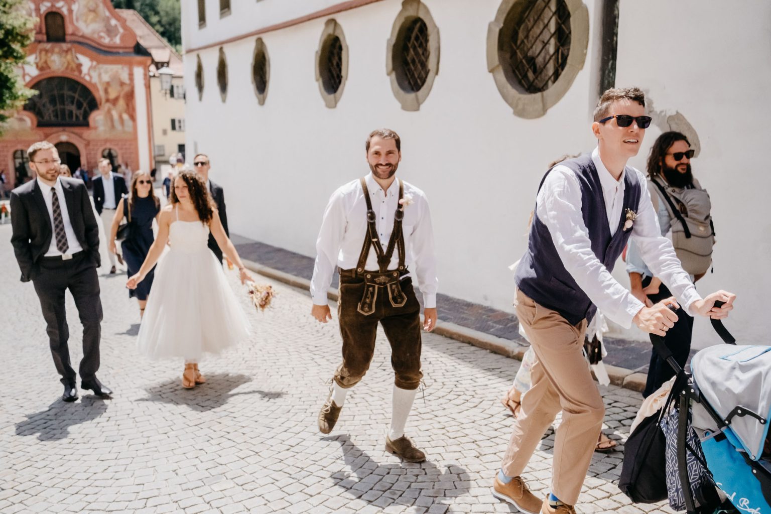 Hochzeitsgesellschaft verlässt die Kirche, im Zentrum der Trauzeuge in Lederhosen.
