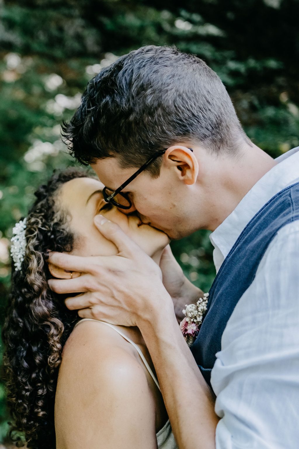 Verspielter Hochzeitsmoment – Bräutigam küsst Braut mit beiden Händen im Gesicht