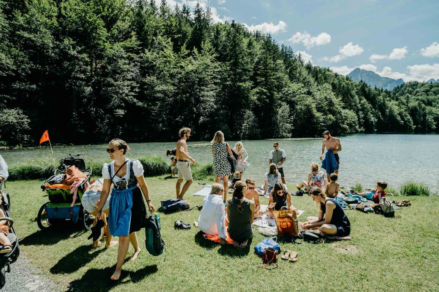 Hochzeitsgesellschaft relaxt am Alatsee – Gäste sitzen im Gras, andere im Wasser