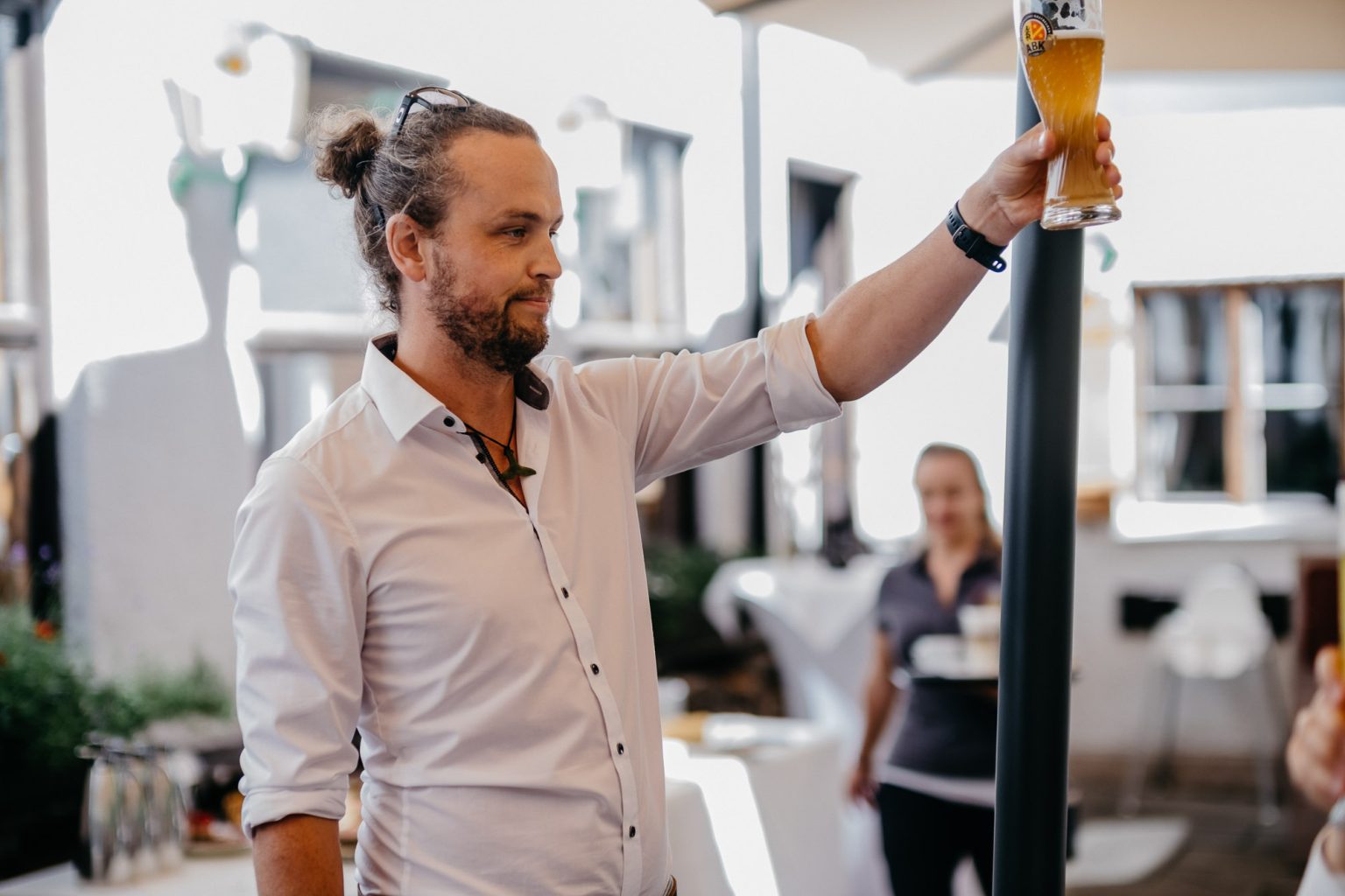 Hochzeitsgast erhebt Glas Weizenbier zum Toast beim Fest am Alatsee