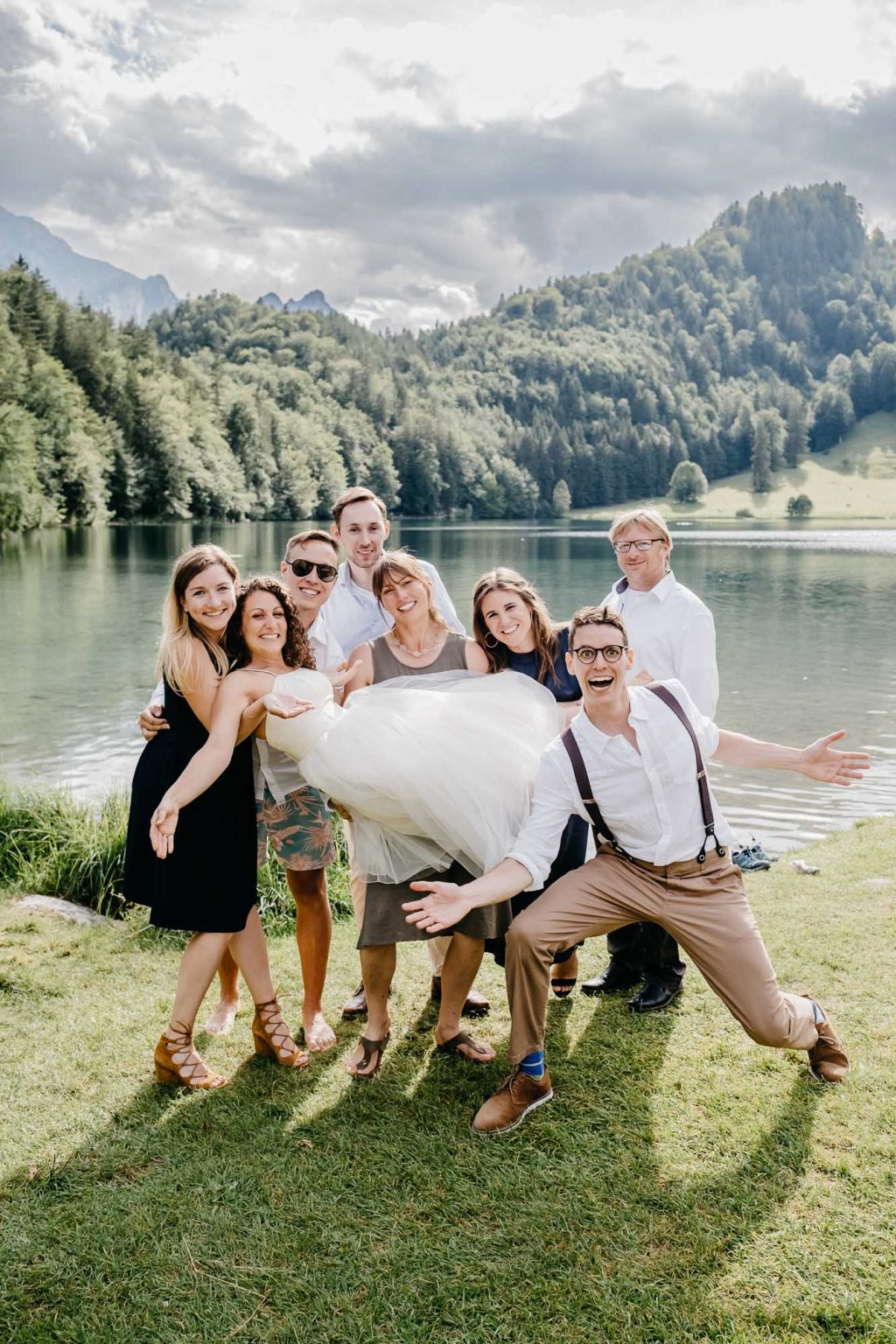 Freunde heben Braut beim Gruppenfoto bei Hochzeit im Allgäu hoch
