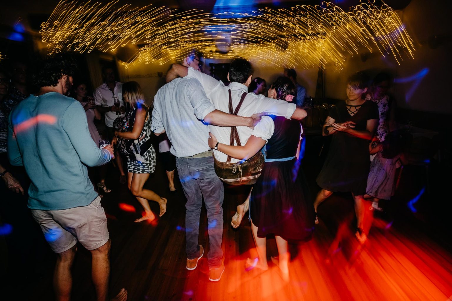 Trauzeuge wird auf den Schultern von zwei Gästen bei der Hochzeitsparty getragen.