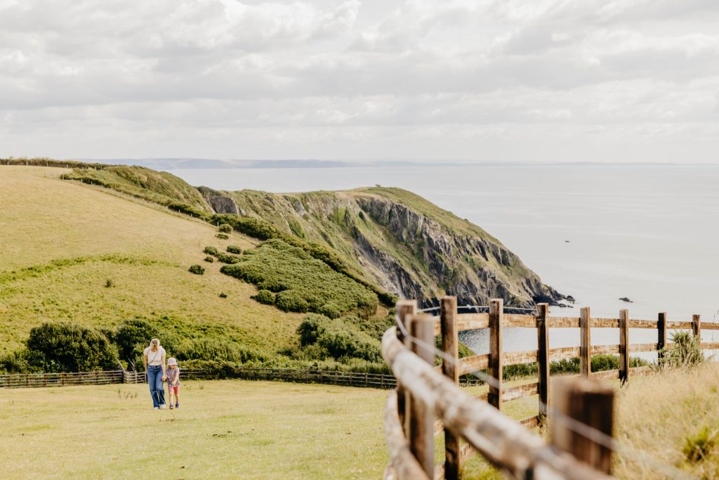 Wanderung entlang der Küste von Mevagissey nach Portmellon und Gorran Haven in Cornwall, Mutter mit Tochter auf dem Küstenpfad mit Blick aufs Meer.